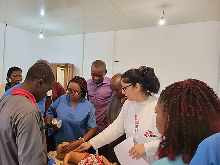 Ärztin erklärt Reanimation an einer Baby-Puppe